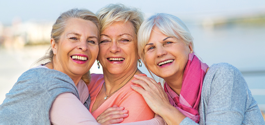 Drei gutgelaunte Freundinen umarmen sich und lachen