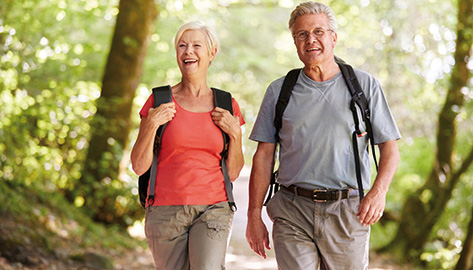 Mann und Frau mit Rucksäcke wandern im Wald und lächeln