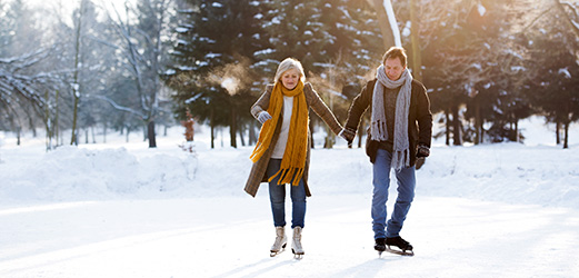 Mann und Frau Hand in Hand beim Eislaufen auf einem See