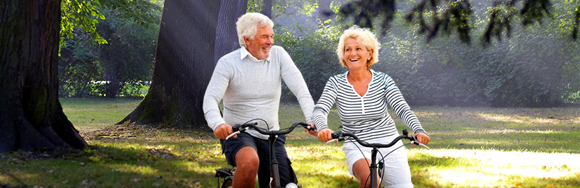 Mann und Frau fahren Fahrrad im Wald und lächeln dabei
