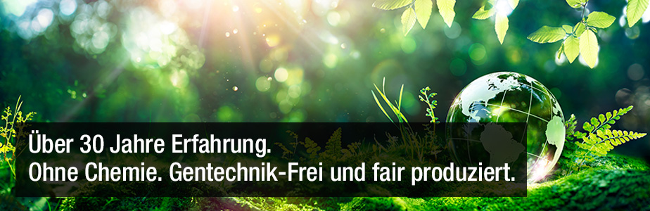 Weltkugel aus Glas liegt auf Gras mit dem Titel: Über 30 Jahre Erfahrung. Ohne Chemie. Gentechnik-Frei und fair produziert