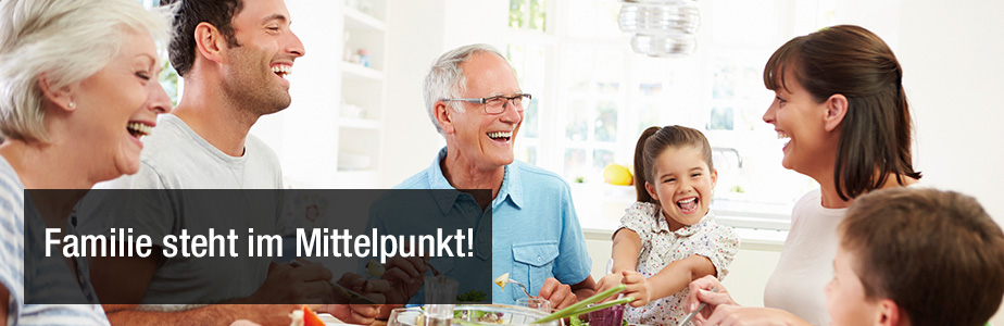 Großmuter, Großvater, Mutter, Vater, Junge und Mädchen lachen beim Essen mit dem Titel: Familie steht im Mittelpunkt!
